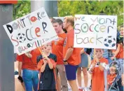  ?? JIM THOMPSON/JOURNAL ?? Cristian Olson, left, and Julian Olson, right, show their support for the UNM men’s soccer team Thursday night at a rally to try to save Lobo sports.