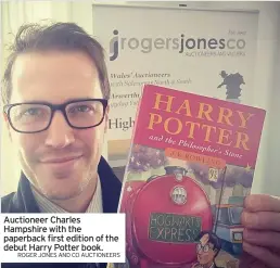  ?? ROGER JONES AND CO AUCTIONEER­S ?? Auctioneer Charles Hampshire with the paperback first edition of the debut Harry Potter book.