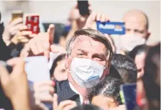  ?? — AFP photo ?? Bolsonaro gestures as he is surrounded by supporters while visiting the residence of an adviser in Brasília.