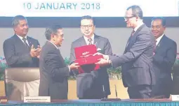  ??  ?? Civil Aviation Malaysia's Director General Azharuddin Abdul Rahman and Ocean Infinity's CEO Oliver Plunkett exchange documents, witnessed by Malaysia's Transport Minister Liow Tiong Lai, during the MH370 search operations signing ceremony between...