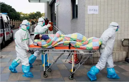  ?? 摄影 陶冉 ?? 2020年1月29日，武汉协和医院西院，医护人员迅速将一位转­院患者推入医院。