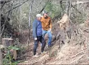  ?? Doug Walker / RN-T ?? Volunteers Steve Kight (left) and Harry Brock check out the stump left by a fallen tree along one of the new terrace trails being developed on Blossom Hill below the city water works.