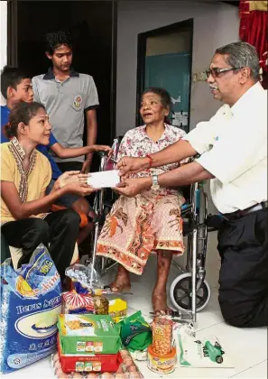  ??  ?? Helping hand: Murugiah (right) handing financial aid to Sri Priya and her family in Ayer Itam after finding out about the family’s plight.