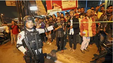  ??  ?? Keep a safe distance: A police officer clearing the scene after an explosion near a bus stop in the Kampung Melayu area of Jakarta. — AP