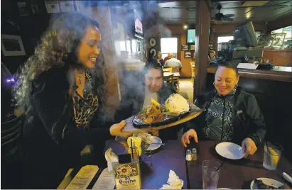  ?? PHOTOS BY KARL MONDON — STAFF PHOTOGRAPH­ER ?? Vanessa Garcia serves a plate of adobo to longtime customers Estelle Paolo and Rolanda Mitchell at the 7 Mile House on Wednesday in Brisbane. The business is the last Peninsula Mile House from the stagecoach days still standing in its original location.