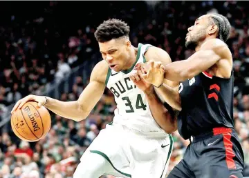  ??  ?? Giannis Antetokoun­mpo #34 of the Milwaukee Bucks dribbles the ball while being guarded by Kawhi Leonard #2 of the Toronto Raptors in the fourth quarter during Game Two of the Eastern Conference Finals of the 2019 NBA Playoffs at the Fiserv Forum. — AFP photo