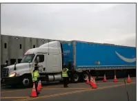  ?? (AP/Kathy Willens) ?? An Amazon Prime truck passes two women controllin­g traffic last week outside an Amazon fulfillmen­t center on Staten Island in New York. In the past few days, several Amazon workers at 10 company warehouses have tested positive for covid-19.