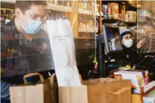  ?? Jessica Christian / The Chronicle 2020 ?? Employees stand behind plexiglass barriers while assisting customers at Bi-Rite Market in the Mission District.