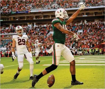  ?? MIKE EHRMANN / GETTY IMAGES ?? Miami’s Lawrence Cager (right) celebrates a touchdown against Virginia. With the nation’s longest winning streak at 15 games, UM seeks an unbeaten regular season today at Pittsburgh.