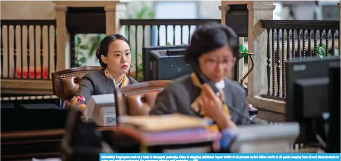  ??  ?? SHANGHAI: Employees work at a bank in Shanghai yesterday. China is slapping additional import tariffs of 25 percent on $16 billion worth of US goods ranging from oil and steel products to autos and medical equipment, the commerce ministry said yesterday. — AFP