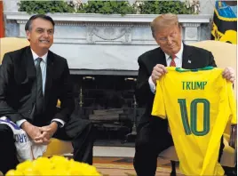  ?? Evan Vucci The Associated Press ?? Brazilian President Jair Bolsonaro gives President Donald Trump a Brazilian national team soccer jersey Tuesday in the Oval Office.