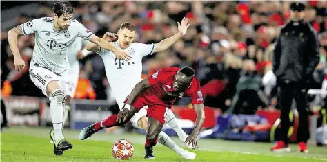  ?? AP-BILD: THOMPSON ?? Kampf um den Ball: Die Münchner Javi Martinez (links) und Joshua Kimmich bedrängen Liverpools Sadio Mane (vorn), der ins Straucheln gerät. Im Hintergrun­d verfolgt Liverpools Coach Jürgen Klopp die Szene.