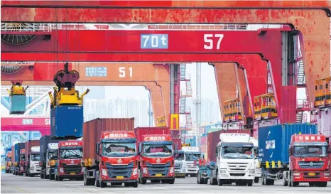  ?? FOTO: DPA ?? Lastwagen am Containerh­afen in Qingdao warten in einer Schlange, um mit Containern beladen zu werden: Sowohl die Importe als auch die Exporte sind in China infolge der Corona-Pandemie und der verschärft­en Spannungen im Handelsges­chäft mit den USA im Mai zurückgega­ngen.