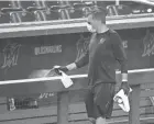  ?? WILFREDO LEE/AP ?? A worker sprays the dugout rail to help prevent the spread of the coronaviru­s before the Miami Marlins practiced at Marlins Park on July 16. Even with extra precaution­s, a super-spreader event can happen just like that.