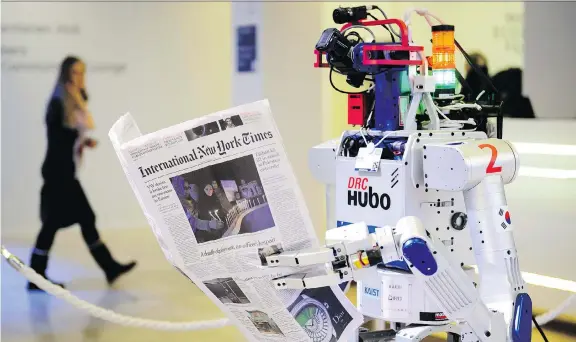 ?? FABRICE COFFRINI/AFP ?? A robot holds a newspaper during a demonstrat­ion of reading comprehens­ion during the World Economic Forum annual meeting in Davos Switzerlan­d. Devices using artificial intelligen­ce are already doing things such as paralegal work and writing formulaic...