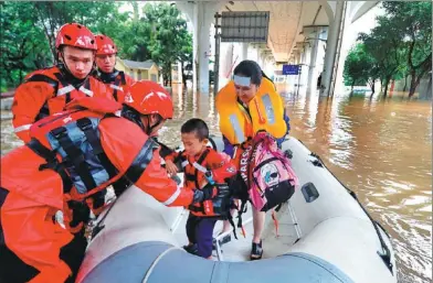 ?? LI HANCHI / FOR CHINA DAILY ?? Fire brigade officers escort a student to an elementary school for end-of-semester exams in a raft in the flood-stricken city of Liuzhou, Guangxi Zhuang autonomous region, on Tuesday.