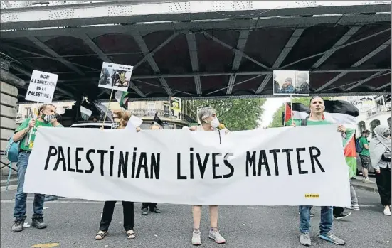  ?? ANADOLU AGENCY / GETTY ?? Protesta amb banderes i pancartes de suport als palestins davant els atacs israelians, ahir a París