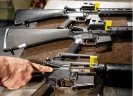  ?? ALEX BRANDON/ASSOCIATED PRESS ?? In a row of AR-15 style rifles, a finger points to the pin of an M-16 that makes it a fully automatic machine gun receiver.