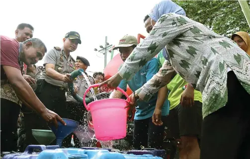  ?? CHUSNUL CAHYADI/JAWA POS ?? MERINGANKA­N: AKBP Wahyu S. Bintoro ikut membagikan air bersih kepada warga di Desa Klampok, Benjeng, kemarin.