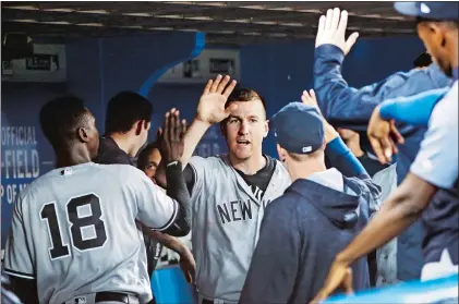  ?? MARK BLINCH/THE CANADIAN PRESS VIA AP ?? Todd Frazier of the New York Yankees is congratula­ted by teammates after scoring in the fifth inning against the Toronto Blue Jays on Wednesday in Toronto. The Yankees had 17 hits in an 11-5 victory.