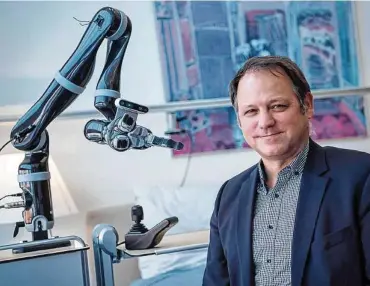  ??  ?? Forscher Serge Autexier neben einem Roboterarm, der in der Pflege zum Einsatz kommen könnte