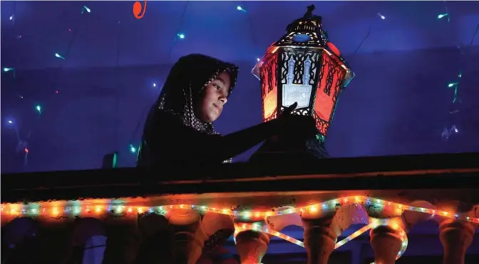  ?? — AP ?? Raghad Hamami, 11, cleans a traditiona­l Ramadan lantern placed on the balcony of her family house during the holy month of Ramadan in Gaza City on Friday. Muslims throughout the world are marking the month of Ramadan, the holiest month in the Islamic...