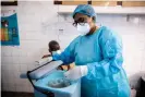  ?? Photograph: Lisa Murray ?? Mimi Henriette Mishika takes an AstraZenec­a vial out of cold storage to begin the first vaccinatio­ns of the day at Kinshasa’s Clinique Ngaliema.