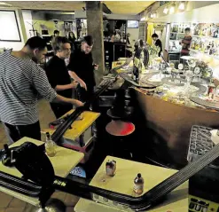  ?? — REUTERS ?? WORK TIME, PLAYTIME Bartenders prepare to race on the electric track for model cars while waiting for takeout orders at Mlynska cafe, which on regular days is popular with Prague’s artist community. Coronaviru­s restrictio­ns are currently keeping customers away.