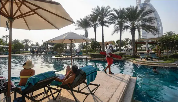  ?? AFP ?? Tourists by the pool at Al Naseem hotel in Dubai. The emirate reopened its doors to the world on Tuesday, more than three months after its airspace was closed