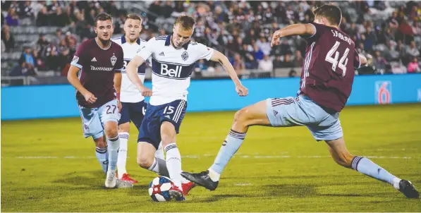  ?? — PHOTOS: JACK DEMPSEY/THE ASSOCIATED PRESS ?? Whitecaps midfielder Andy Rose scores the game-winning goal as Colorado Rapids’ Deklan Wynne, left, and Axel Sjoberg try to defend during the second half of an MLS soccer match Friday in Commerce City, Colo.