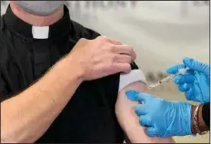  ??  ?? A Catholic priest receives the first of the two Pfizer-BioNTech covid-19 vaccinatio­ns at a hospital in Chicago in this Dec. 23 photo. In a growing consensus, religious leaders at the forefront of the anti-abortion movement in the United States are telling their followers that the leading vaccines available to combat covid-19 are acceptable to take, given their remote and indirect connection to lines of cells derived from aborted fetuses. (AP/Charles Rex Arbogast)