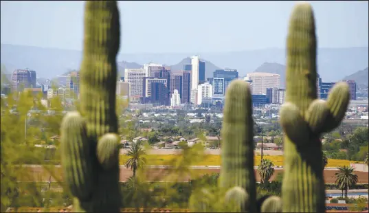  ?? ROSS D. FRANKLIN / ASSOCIATED PRESS FILE (2020) ?? The downtown Phoenix skyline is framed by saguaro cactus in April of 2020.