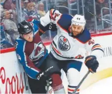  ?? David Zalubowski, The Associated Press ?? Oilers forward Zack Kassian checks Avs defenseman Anton Lindholm along the boards Sunday. Lindholm is sidelined after being injured in the game.