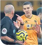  ??  ?? Referee Mike Dean tells Conor Coady of the VAR decision