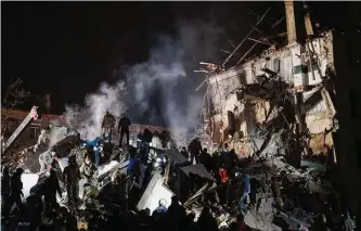  ?? Yevgen Honcharenk­o/associated Press ?? Emergency workers and residents work after a Russian rocket hit apartments Thursday in Kramatorsk, Ukraine. Russian strikes there also hit a children’s clinic, an official said.