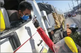  ??  ?? A health official checks the temperatur­e of a truck driver delivering rice to a government warehouse last week in Manila. The Philippine­s plans to buy rice from Thailand and Vietnam under a government-to-government deal to help boost supply during lean months.
Bloomberg News/Veejay Villafranc­a