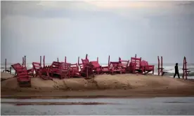  ?? Photograph: Félix Márquez/AP ?? A man walks past tied up chairs at the Miramar beach as Hurricane Ingrid approaches the coast in Ciudad Madero, Mexico, in 2013, the year the municipali­ty erected a bust of a green Martian.