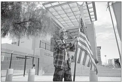  ?? AP/JOHN LOCHER ?? David Fleeman, a supporter of Cliven Bundy and his co-defendants, holds a flag outside the federal courthouse in Las Vegas on Monday. Juror selection began in the trial stemming from an armed standoff with federal agents in 2014.