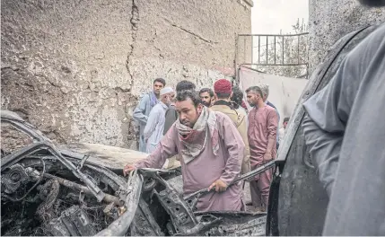  ?? ?? AFTERMATH: Relatives and neighbours inspect damage in the cramped courtyard of a house in Kabul, Afghanista­n, which they said was caused by a US drone strike.