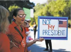  ?? Lea Suzuki / The Chronicle ?? A protester joins others on Alpine Road hoping to catch Trump’s eye as he drives to his Portola Valley fundraiser.