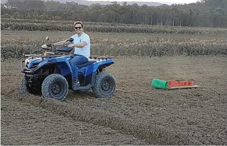  ?? PHOTO: CONTRIBUTE­D ?? NEW METHOD: Queensland Drones employee Chris Hallows pulls the electromag­netic soil meter through a pineapple field to get a closer look at the soil’s attributes.