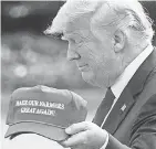  ?? NICHOLAS KAMM/ AFP/ GETTY IMAGES ?? President Donald Trump shows a new hat as he heads for Indiana in 2018.