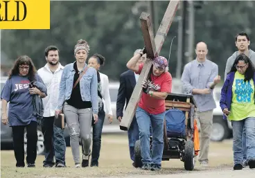  ?? ERIC GAY / THE ASSOCIATED PRESS ?? Stephen Hope carries a cross Sunday following a service for the victims of the Sutherland Springs, Texas, church shooting. “Rather than choose darkness as that young man did that day, we choose life,” said Pastor Frank Pomeroy.