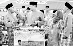  ??  ?? Hishammudd­in (second left) feeds Mohd Khusairi yellow glutinous rice in conjunctio­n with his birthday during the Tanjung Malim Umno Delegates’ Conference. — Bernama photo