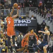  ?? AP Photo ?? Raptors forward Serge Ibaka shoots late in double overtime against Wizards forward Otto Porter Jr. (22) and guard Tomas Satoransky Sunday.