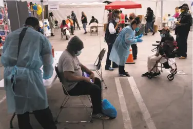  ?? Jae C. Hong / Associated Press ?? omeless people wait for their C%V DŽ1¥ vaccinatio­ns at a site set çp in a parking lot in the Skid 0ow area of Los Angeles. Shots are finally reaching thoçsands of yoçnger adçlts who are homeless.