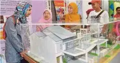  ??  ?? NORAIDA (dua dari kiri) bersama pengunjung melihat model rumah yang dipamerkan.