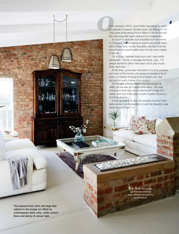  ??  ?? The exposed brick walls and large teak cabinet in the lounge are offset by contempora­ry white sofas, white cement floors and plenty of natural light. We love the built-in gas fireplace that has been cleverly worked into the brickwork.