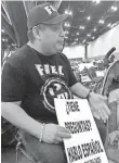  ?? ELLIOT SPAGAT, AP ?? Alain Cisneros of the advocacy group Immigrant Families and Students in the Struggle counsels evacuees at Houston’s George R. Brown Convention Center. His sign reads, “Do you have questions?”