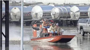  ??  ?? Gabe Schmidt, owner of Liquid Trucking, top right, travels by airboat to survey damage from Platte River flooding in Plattsmout­h, Neb.